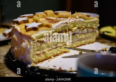Nahaufnahme eines mehrschichtigen Kuchens mit Dekorationen auf einem Teller Mit einem Kuchenserver darauf Stockfoto