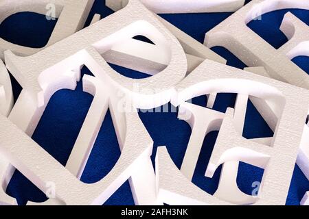 Weiße Buchstaben ausschneiden aus Schaumstoff ohne Lackierung auf einem blauen Hintergrund. Leer, für die Dekoration, Logo, Stockfoto