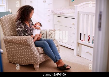 Liebevolle Mutter sitzt im Sessel kuscheln Baby Sohn im Kindergarten zu Hause Stockfoto