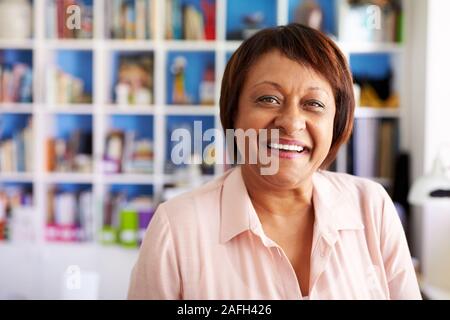 Portrait von lächelnden reife Frau im Home Office durch Bücherregal Stockfoto