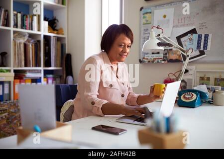 Lächelnd reife Frau mit Laptop arbeiten im Home Office Stockfoto