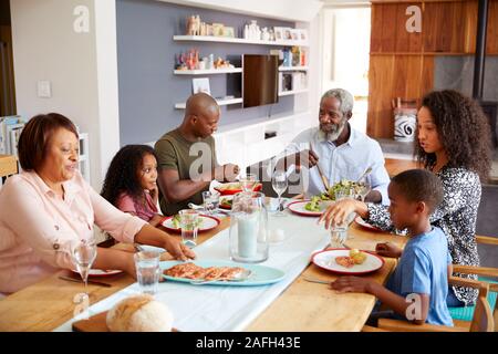 Multi-Generation Familie sitzt um den Tisch zu Hause genießen Mahlzeit zusammen Stockfoto