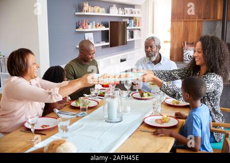 Multi-Generation Familie sitzt um den Tisch zu Hause genießen Mahlzeit zusammen Stockfoto