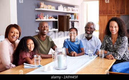 Portrait von Multi-Generation Familie zusammen um den Tisch zu Hause genießen Essen sitzen Stockfoto