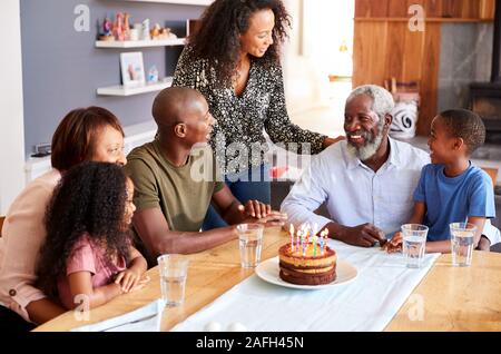 Multi-Generation Familie feiert Geburtstag der Großväter zu Hause mit Kuchen und Kerzen Stockfoto
