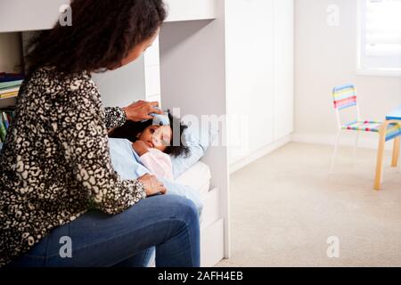 Mutter Pflege für kranke Tochter krank im Bett mit Temperatur Stockfoto