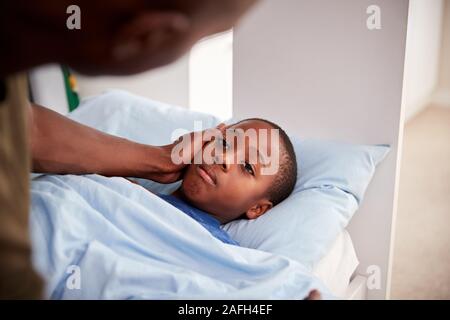 Vater die Sorge für die Kranken Sohn lag krank im Bett zu Hause Stockfoto