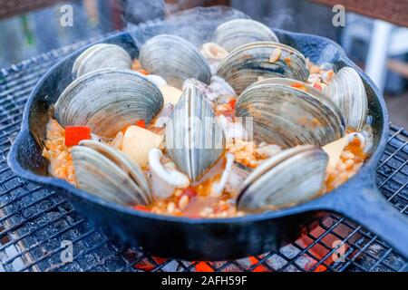 Nahaufnahme des Prozesses des Grillens einer Paella mit Schnecken Stockfoto