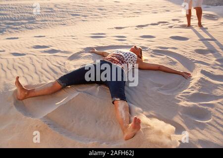 Senior liegende Frau am Strand, Sand Engel auf Urlaub Stockfoto