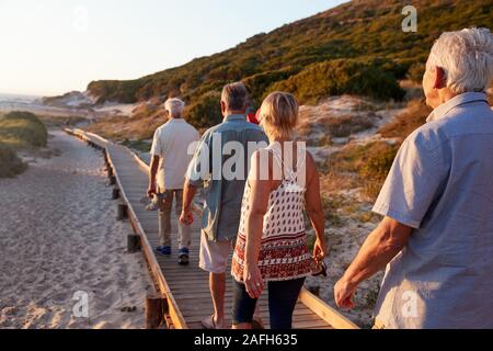 Gruppe von älteren Freunden zu Fuß entlang der Promenade am Strand im Sommer Gruppe Ferienhäuser Stockfoto