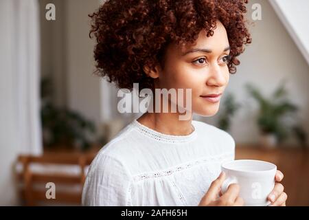 Junge Frau Entspannen im Loft Apartment mit heißen Getränken Stockfoto