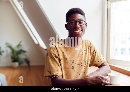 Portrait des jungen Mannes, Entspannen im Loft Apartment mit heißen Getränken Stockfoto