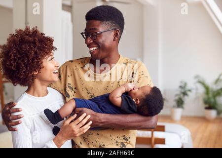 Liebevolle Eltern mit neugeborenen Babys zu Hause in Loft Apartment Stockfoto