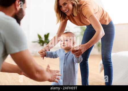 Eltern zu Hause Förderung Baby Sohn Erste Schritte Stockfoto