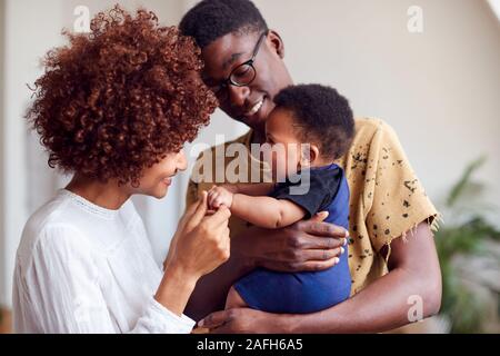 Liebevolle Eltern spielen Mit neugeborenen Babys zu Hause in Loft Apartment Stockfoto