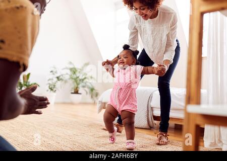 Eltern zu Hause Förderung Baby Tochter Erste Schritte Stockfoto