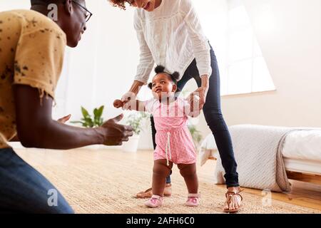 Eltern zu Hause Förderung Baby Tochter Erste Schritte Stockfoto