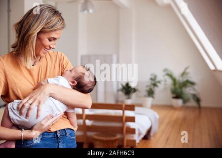 Liebevolle Mutter, neugeborenes Baby zu Hause in Loft Apartment Stockfoto