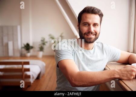Portrait des jungen Mannes, Entspannen im Loft Apartment mit heißen Getränken Stockfoto