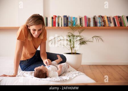 Liebevolle Mutter mit Baby liegend auf Bett zu Hause in Loft Apartment Stockfoto