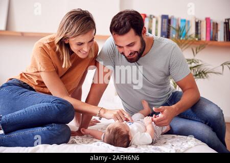 Liebevolle Eltern mit neugeborenen Baby liegend auf Bett zu Hause in Loft Apartment Stockfoto