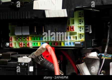 Mehrfarbige Sicherungskasten im Stromkreis des Autos während der Reparatur in der Werkstatt. Auto Service Industrie. Stockfoto