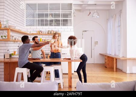 Zwei Paare, die Entspannung in der Küche zu Hause einen Toast mit einem Glas Wein zusammen Stockfoto