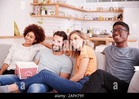 Eine Gruppe von Freunden auf dem Sofa sitzen und beobachten Film zu Hause essen Popcorn Stockfoto