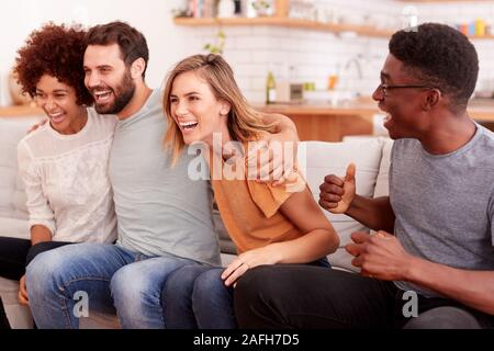 Aufgeregt Gruppe von Freunden sitzen auf dem Sofa und Sport Beobachten auf TV Stockfoto