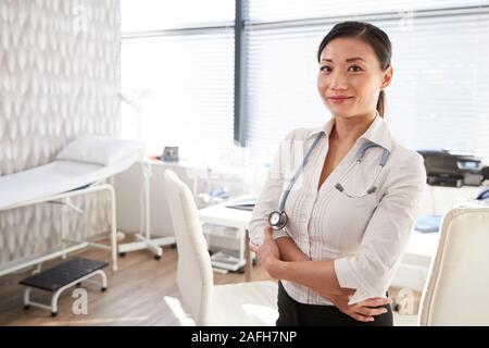 Portrait von lächelnden Frau Doktor mit Stethoskop stehen Schreibtisch im Büro Stockfoto