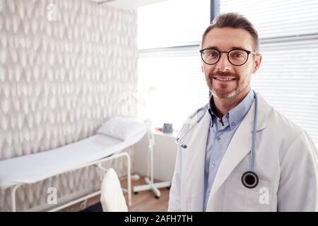 Portrait von lächelnden Reife männlicher Arzt tragen weiße Mantel mit Stethoskop im Büro Stockfoto