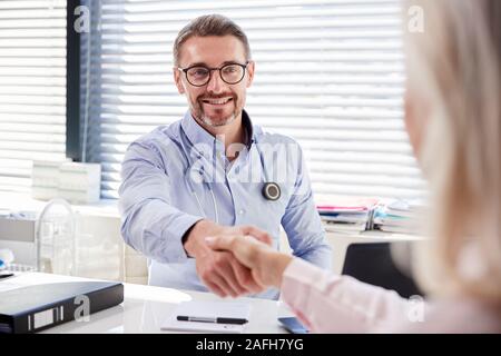 Weibliche Patienten Händeschütteln mit Arzt Sitzen am Schreibtisch im Büro Stockfoto