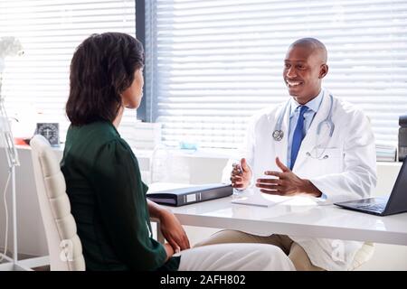 Weibliche Patienten in Absprache mit dem Arzt Sitzen am Schreibtisch im Büro Stockfoto