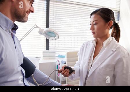 Männliche Patienten, der Blutdruck durch Ärztin in Office Stockfoto