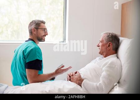 Chirurg besuchen und das Gespräch mit älteren männlichen Patienten im Krankenhausbett in Geriatrische Einheit Stockfoto