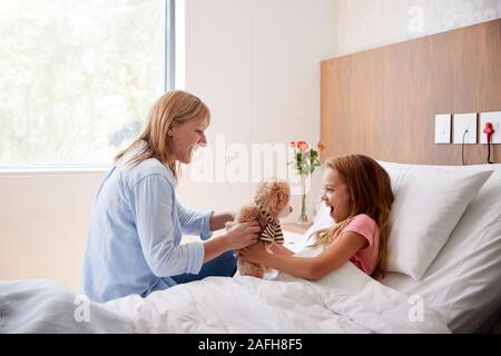 Mutter und Tochter liegt in einem Krankenhausbett Geschenk der Teddybär während des Besuchs Stockfoto