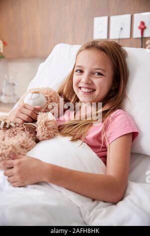 Portrait von Mädchen liegt im Bett im Krankenhaus umarmen Teddybär Stockfoto
