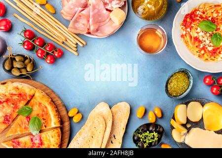 Italienisches Essen Hintergrund. Pizza, Pasta, Käse, Schinken, Wein, Oliven, Pesto, Kapern, Schuß von der Oberseite, bilden einen Rahmen für Kopie Platz, einen Flach Stockfoto