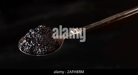 Schwarze Kaviar Panorama, einen Löffel closeup auf einem dunklen Hintergrund mit einem Platz für Text Stockfoto