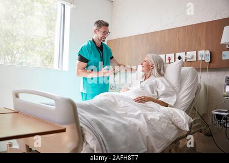 Chirurg besuchen und das Gespräch mit Reife Weibliche Patienten im Krankenhaus Bed Stockfoto