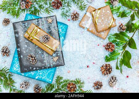 Top View oder flach Bild mit Weihnachtsgeschenke auf Schnee mit Weihnachten Dekoration als Fir Tree Branch und Kegel Kiefern. Kopieren oder leeren Raum für Text. Stockfoto