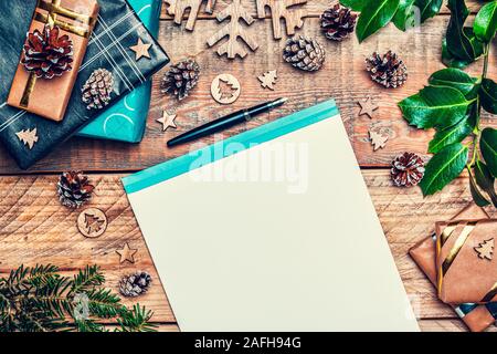 Weihnachten Brief an Santa Claus Konzept. Flach Komposition mit Schreiben, Papier, Stift, Kegel Kiefern, eingepackte Geschenke und xmas Dekoration. Stockfoto