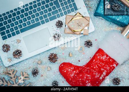 Flach oder Blick von oben auf die Laptop Tastatur, Geschenke und rot Santa Claus Socke auf Kunstschnee. Online Shopping für Weihnachten Konzepte. Stockfoto