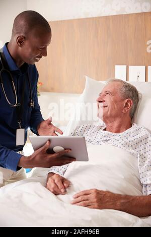 Arzt mit digitalen Tablet besuchen und das Gespräch mit älteren männlichen Patienten im Krankenhaus Bed Stockfoto