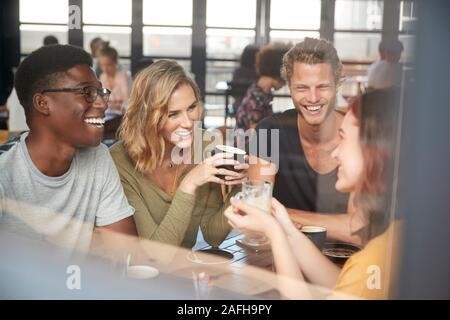 Gruppe von Freunden Sitzen am Tisch im geschäftigen Coffee Shop Sprechen Stockfoto