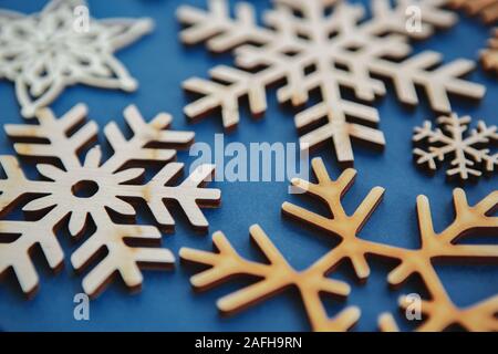 Handgefertigten Holzmöbeln Schneeflocken auf blauem Hintergrund Weihnachten und Neujahr home Dekorationen aus ökologischen Naturholz gefertigt. Handgefertigte Schnee fla Stockfoto