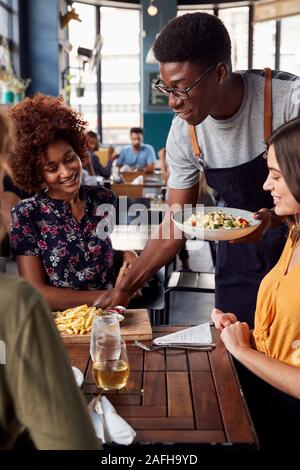 Kellner, die Gruppe der weiblichen Freunde treffen für Getränke und Essen im Restaurant Stockfoto