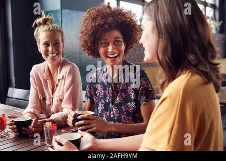 Drei junge weibliche Freunde Treffen sitzen an einem Tisch in Cafe und Reden Stockfoto