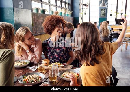 Vier junge weibliche Freunde treffen für Essen und Getränke Posieren für Selfie im Restaurant Stockfoto