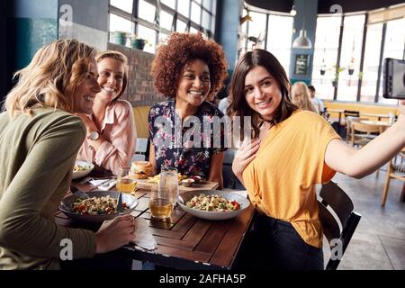 Vier junge weibliche Freunde treffen für Essen und Getränke Posieren für Selfie im Restaurant Stockfoto